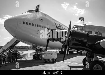 BERLIN, 28. APRIL 2018: Verkehr Flugzeug Junkers Ju 52/3 m (Vordergrund) und der großraumflugzeuge Jet Airliner Boeing 747-8 (Hintergrund). Lufthansa. Schwarz und Weiß. Ausstellung die ILA Berlin Air Show 2018. Stockfoto