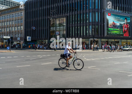 BERLIN - Juni 09, 2018: Ein einsamer Radfahrer auf einer großen Kreuzung. Stockfoto
