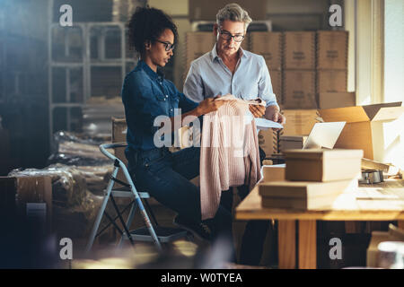 Frau, das Produkt zu Ihrem Partner vor dem Verpacken und dem Kunden übergeben wird. Online Vertrieb von Business Partnern zusammen in den offic arbeiten Stockfoto