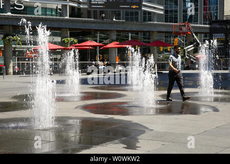 Toronto, Kanada. 27 Juni, 2019. Ein Mann hinter den Wasserfontänen während eines heißen und sonnigen Tag in Toronto. Die Temperatur auf 30 Grad Celsius noch in dieser Woche zu steigen. Credit: SOPA Images Limited/Alamy leben Nachrichten Stockfoto