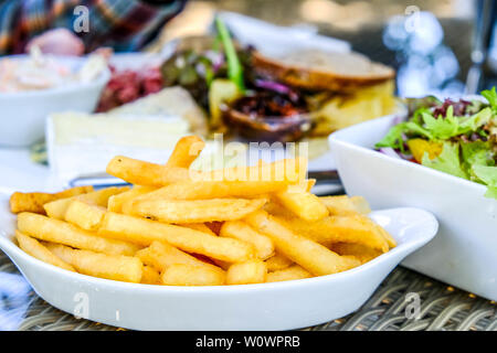 Schüssel Chips oder Pommes Frites In einer Aufstellung im Freien mit einer gemischten Grünen Garten Salat Stockfoto