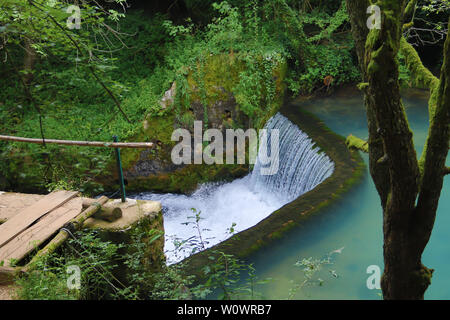 Erstaunlich schöne Bergquelle mit himmlischen blauen Wasser Farbe und kleinen Wasserfall namens Krupajsko Vrelo (Frühjahr Krupaj) Stockfoto