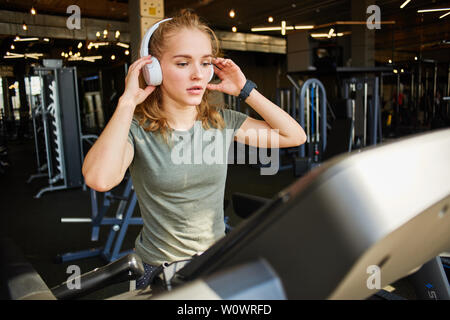 Mädchen beendet cardio Training auf dem Laufband und hält Ihre Kopfhörer. Stockfoto