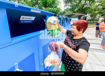 Chongqing, China. 27 Juni, 2019. Ein Bewohner setzt Hausmüll in eine Müll sortiert kann an eine Gemeinde im Bezirk Jiulongpo in Chongqing, im Südwesten von China, 27. Juni 2019. Chongqing hat sich bemüht, Müll sortieren in den letzten Jahren zu fördern. Eine garbage Klassifizierungssystem hat 680.000 Haushalte von 1.796 Gemeinden in 39 Straßen und Orte in der Innenstadt von Chongqing abgedeckt. Credit: Liu Chan/Xinhua/Alamy leben Nachrichten Stockfoto