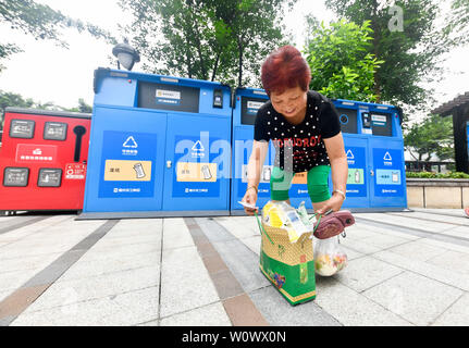 Chongqing, China. 27 Juni, 2019. Ein Bewohner ordnet Hausmüll in der Nähe von Mülltonnen an eine Gemeinde im Bezirk Jiulongpo in Chongqing sortiert, im Südwesten von China, 27. Juni 2019. Chongqing hat sich bemüht, Müll sortieren in den letzten Jahren zu fördern. Eine garbage Klassifizierungssystem hat 680.000 Haushalte von 1.796 Gemeinden in 39 Straßen und Orte in der Innenstadt von Chongqing abgedeckt. Credit: Liu Chan/Xinhua/Alamy leben Nachrichten Stockfoto