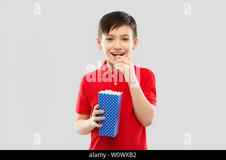 Lächelnde Junge im roten T-Shirt essen Popcorn Stockfoto