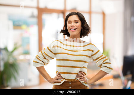 Lächelnde Frau in Pullover mit Händen auf den Hüften Stockfoto