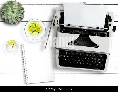 Blick von oben auf die alte Schreibmaschine, sukkulenten Pflanzen, Wasser, Karaffe und Notizblock auf rustikalen weiße Holztisch Stockfoto
