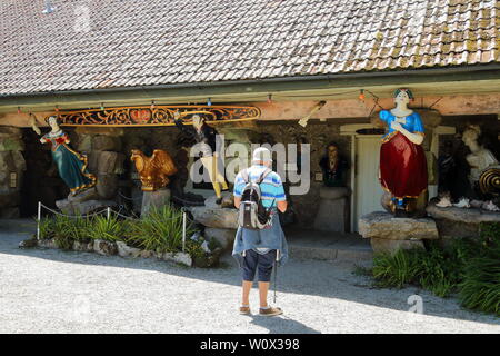 Ein Touristen bewundert Holzschiff Galionsfiguren aus versunkenen Schiffen bei Valhalla in Abbey Gardens, Tresco, Isles of Scilly, Cornwall, UK angezeigt geschnitzt Stockfoto