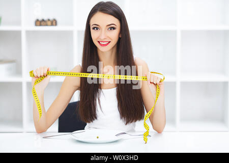 Diät. Glückliche junge lächelnde Frau über eine Erbse Halteplatte und Gabel mit Massband zu essen. Stockfoto