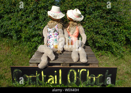 Halsall, Lancashire. 28. Juni 2019. UK Wetter. Cocktail o'clock als Paar sonnigen Sommer Skulpturen über Nacht erscheinen. Groteske, skurrile, Stroh gefüllt Vogelscheuchen, film Zeichen, Karikaturen mit unheimlichen maskierten Gesichter, säumen die Straßen und Felder der ländlichen Dorf Halsall. Credit: MWI/AlamyLiveNews Stockfoto