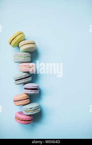 Kuchen Macaron oder Makronen auf Pastell-blaue Hintergrund von oben. Mehrfarbige almond Cookies von Pastellfarben. Ansicht von oben. Stockfoto