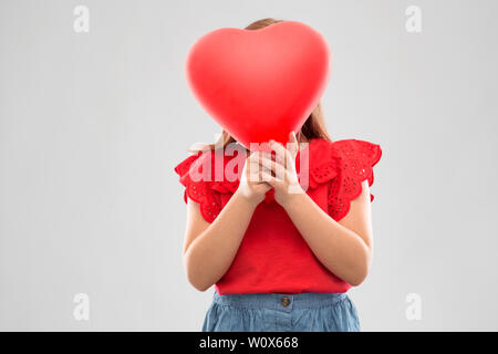 Mädchen versteckt sich hinter rote herzförmige Ballons Stockfoto