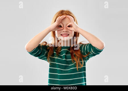 Rothaarige Mädchen schauen durch Finger Gläser Stockfoto