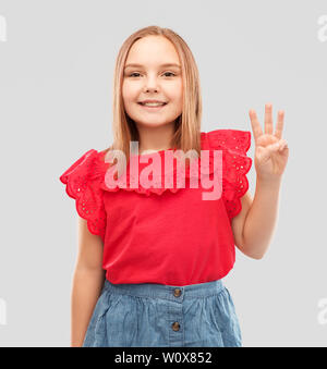 Lächelnde Mädchen in rot Shirt zeigen drei Finger Stockfoto