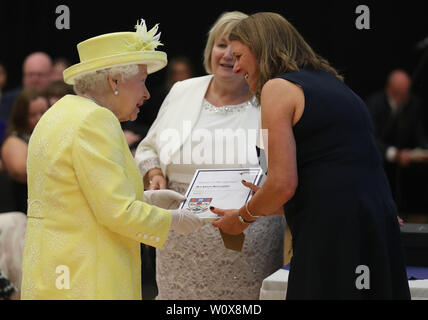 Königin Elizabeth II. stellt Lehrer Eileen McLoughlin mit einer Auszeichnung bei einem Besuch in Greenfaulds High School im Westen von Cumbernauld. Stockfoto