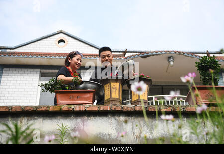 (190628) - chongqing, 28. Juni 2019 (Xinhua) - Liu Yi (R) und seine Frau Lu Kai Wasser Blumen im Innenhof ihres Hauses im Nanchuan Bezirk, im Südwesten Chinas Chongqing, 27. Juni 2019. Trotz verlor seinen rechten Arm bei einem Unfall im Alter von neun Jahren, 44-jährige Liu Yi hat nie seinen Kopf in Richtung Schicksal abgesenkt. Nach Abschluss einer beruflichen Schule im Jahre 1994, versuchte er, eine gute viele Arbeitsplätze wie Spülmaschine, Obst Händler und coal Miner. Seit 2010 hat er beschlossen, sein eigenes Geschäft in seiner Heimatstadt zu beginnen, durch die Organisation von Dorfbewohnern Bambus Wurzeln zu Pflanzen und Hühner. Seine Bemühungen der bezahlten Stockfoto