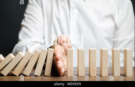 Geschäftsmann stoppt Domino fallen. Risk Management Konzept. Erfolgreiche Unternehmen und Problemlösung. Zuverlässige Führer. Stoppen Sie den zerstörenden Verfahren Stockfoto