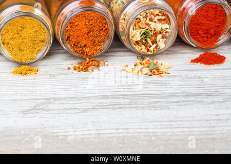 Bunten Gewürzen aus Lügen lügen Gläser. Gewürze und freien Platz auf einer hölzernen Arbeitsplatte. Gefriergetrocknetes Gemüse, Gewürzpaprika, Curry. Stockfoto