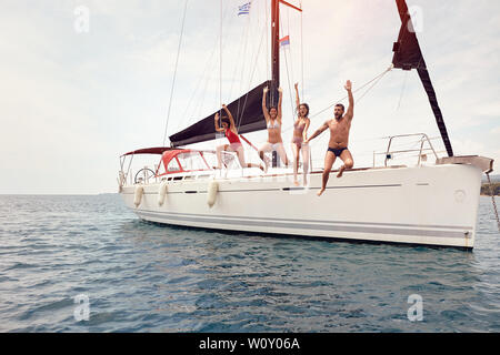 Junge Freunde springen von Segelboot in See. Stockfoto