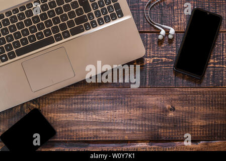 Aktuelle technologische Elemente, Laptop, Mobiltelefon, Kopfhörer und externe Festplatte auf einem rustikalen Holztisch Stockfoto