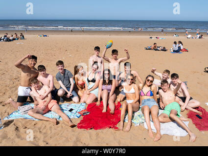 Portobello, Schottland, Großbritannien. 28 Juni, 2019. Warme Temperaturen und ununterbrochenen Sonnenschein brachte Hunderte von Menschen und Familien zu diesem berühmten Strand ausserhalb von Edinburgh. Bild, Gruppe von Jugendlichen die Sonne genießen. Credit: Iain Masterton/Alamy leben Nachrichten Stockfoto