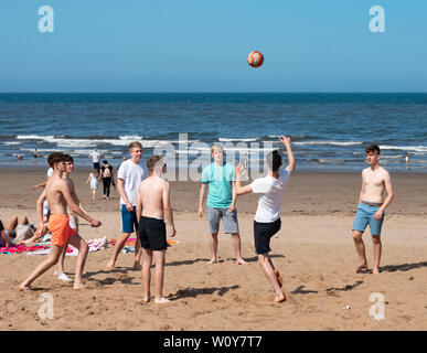 Portobello, Schottland, Großbritannien. 28 Juni, 2019. Warme Temperaturen und ununterbrochenen Sonnenschein brachte Hunderte von Menschen und Familien diesem berühmten Strand ausserhalb von Edinburgh zu genießen. Jugendliche spielen mit Fußball am Strand. Credit: Iain Masterton/Alamy leben Nachrichten Stockfoto