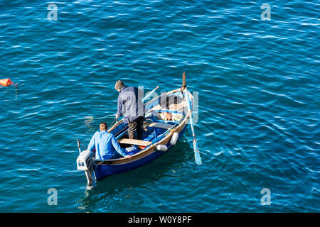 Zwei Fischer auf einem kleinen hölzernen Boot kommen heraus, zu Fisch aus dem kleinen Hafen von Riomaggiore, Cinque Terre, Ligurien, Italien Stockfoto