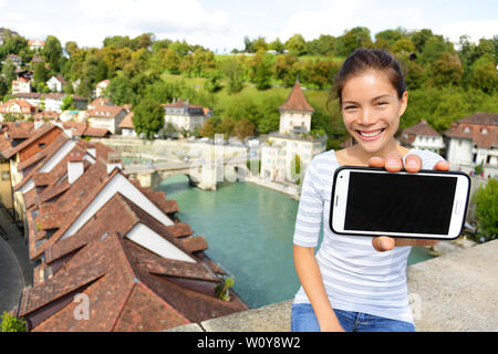 Frau, smart phone-App in Bern, Schweiz, Europa. Mädchen, dass leere leere Bildschirm des Smartphones auf Reisen mit kopieren. Gerne asiatische Mädchen im schweizerischen Bern. Fokus auf dem Bildschirm und Mädchen. Stockfoto