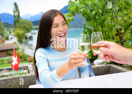 Menschen Spaß trinken Weißwein zum Abendessen zu lachen. Romantisches Paar am Tisch sitzen in den Schweizer Alpen am See in der Schweiz. Romantisches Paar toasten Wein genießen. Stockfoto