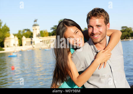 Romantisches Paar portrait in Liebe auf Kamera schaut. Multirassischen Frau und Mann am See im El Retiro in Madrid, Spanien, Europa lächelte glücklich. Stockfoto