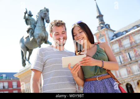 Madrid Touristen mit Tablet Travel App Ratgeber ebook auf der Plaza Mayor durch die Statue von König Philipp III. Touristische paar Sehenswürdigkeiten besuchen Tourismus Sehenswürdigkeiten und Attraktionen in Spanien. Junge Frau und Mann Stockfoto