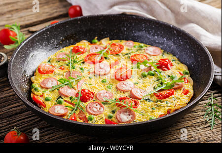 Omelett mit Tomaten, Wurst und grüne Erbsen im rustikalen Stil. Frittata - italienische Omelette. Stockfoto