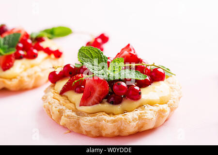Kuchen mit Erdbeeren, Johannisbeeren und Sahne mit Minze dekoriert. Stockfoto