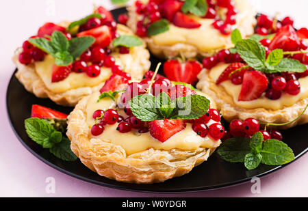 Kuchen mit Erdbeeren, Johannisbeeren und Sahne mit Minze dekoriert. Stockfoto