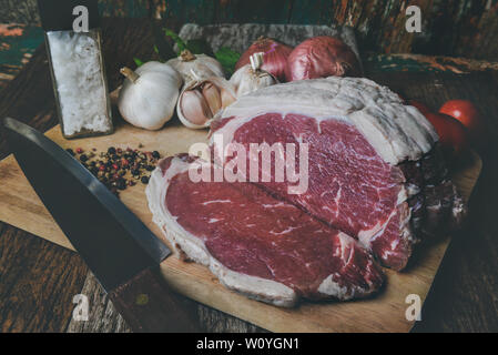 Rohes Rindfleisch Schneiden für Steak mit Gewürz Zutat auf Holzplatte mit grauen und dunklen gedämpfte Beleuchtung. Stockfoto