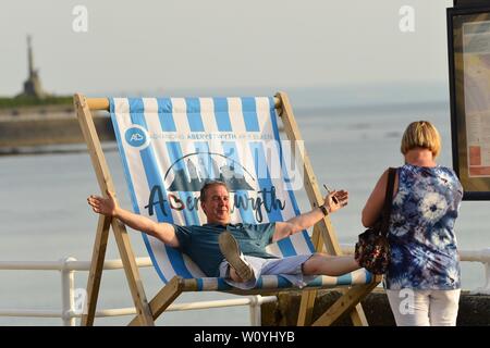 Aberystwyth, Wales, UK. 28. Juni 2019. UK Wetter: Menschen am Meer in Aberystwyth an einem drückend Sommer Abend nach einem Tag der unversehrten blauen Himmel und warmen Sonnenschein. Das Land ist in Richtung der heißeste Tag des Jahres so weit wie eine Feder der glühend heiße Luft driftet in vom Kontinent. Foto Keith Morris/Alamy leben Nachrichten Stockfoto