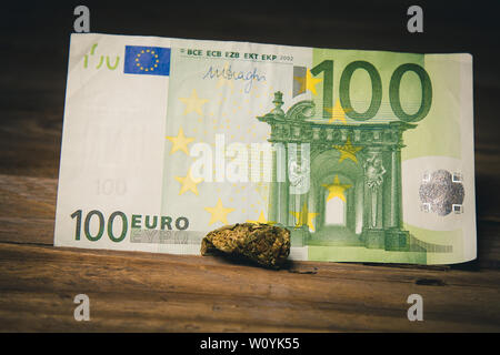 Ein Cannabis bud liegt auf einem hundert Euro bill Close-up. Kauf und Verkauf der Legalisierung weicher Drogen. medizinischen Cannabis Geschäftskonzept. Stockfoto
