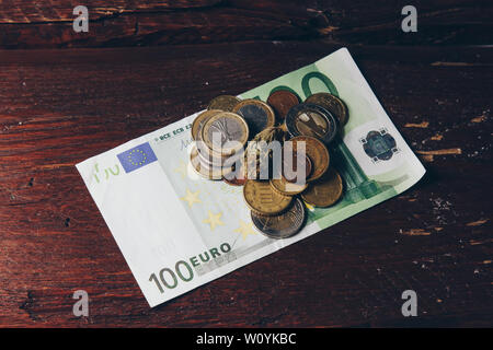 Ein Cannabis bud liegt auf einem hundert Euro Bill und Münzen. Kauf und Verkauf der Legalisierung weicher Drogen. medizinischen Cannabis Geschäftskonzept. Stockfoto