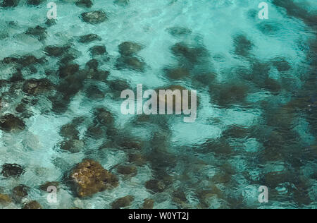 In der Nähe von Felsen auf dem Meeresboden durch klare blaue Wasser mit Sand dazwischen. Stockfoto