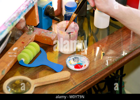 Mann Maler ist das Mischen von Farben vor dem malerei Kunst lack Studio. Künstler in seiner Hand hält Pinsel Farbe Ölfarben für Malerei auf der Palette gemischt. Stockfoto