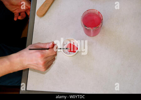 Mann Maler ist das Mischen von Farben vor dem malerei Kunst lack Studio. Künstler in seiner Hand hält Pinsel Farbe Ölfarben für Malerei auf der Palette gemischt. Stockfoto