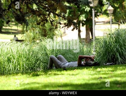 Madrid, Spanien. 28 Juni, 2019. Ein Mann liegt im Schatten auf dem Rasen eines Parks in Madrid, Spanien, 28. Juni 2019. Die Temperatur von Madrid Hit 41 Grad Celsius am Freitag. Quelle: Guo Qiuda/Xinhua/Alamy leben Nachrichten Stockfoto