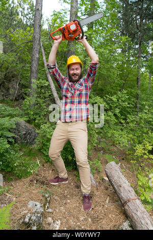 Bärtigen Holzfäller mit einer Kettensäge macht Gesichter Stockfoto