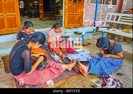 BAGAN, MYANMAR - 24. FEBRUAR 2018: Weibliche Handwerker von lackwaren Werkstatt arbeiten mit Lack Stücke, die traditionelle feine Muster aon Geschirr Stockfoto