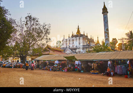 BAGAN, MYANMAR - 24. FEBRUAR 2018: Die Stände von Kleidungsstück Markt, am Eingang des mittelalterlichen Manuha Tempel mit hohen Buddhistischen Säule und Stockfoto