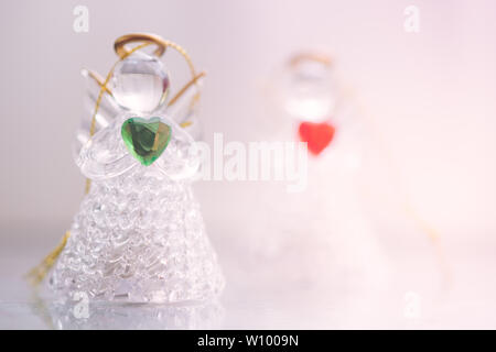 Zwei kleine Glas Engel Statuetten mit Herzen in ihren Händen. Das Konzept der Frieden, Güte und Liebe. Engel immer in der Nähe von uns. Stockfoto