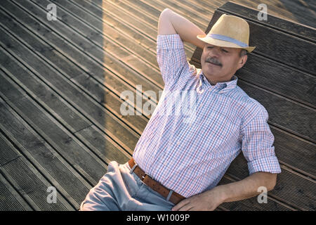 Mann sitzt auf der Bank, Schlaf genießen Sommer sonnigen Tag. Stockfoto