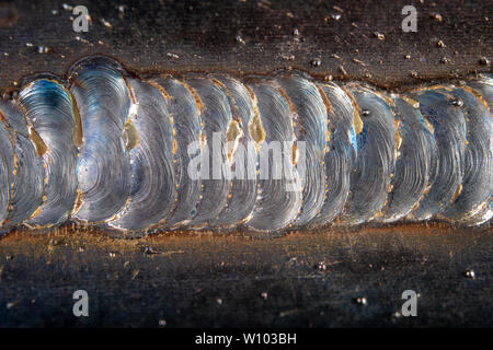 Die Kehlschweißung wird mit der MAG-Methode gelegt. Fehler in Stahl Verbindungen mittels arc welding. dunklen Hintergrund. Stockfoto