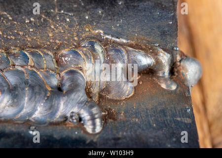 Die Kehlschweißung wird mit der MAG-Methode gelegt. Fehler in Stahl Verbindungen mittels arc welding. dunklen Hintergrund. Stockfoto